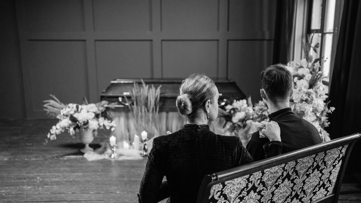 A somber scene of a couple at a funeral, expressing sorrow.
